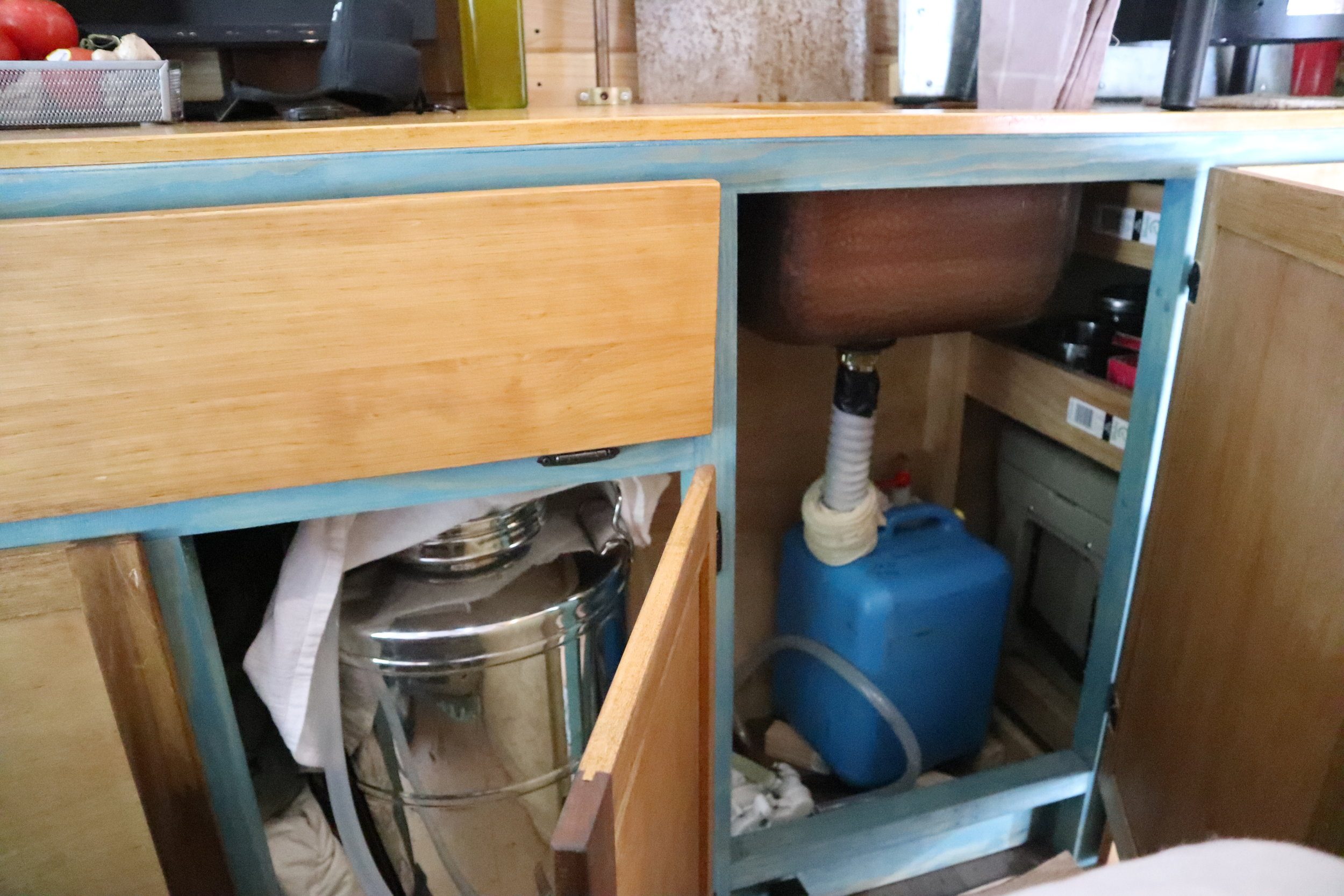 Silver tank = 14 gallons of fresh water. Blue tank = grey water. A foot pump moves the water along.