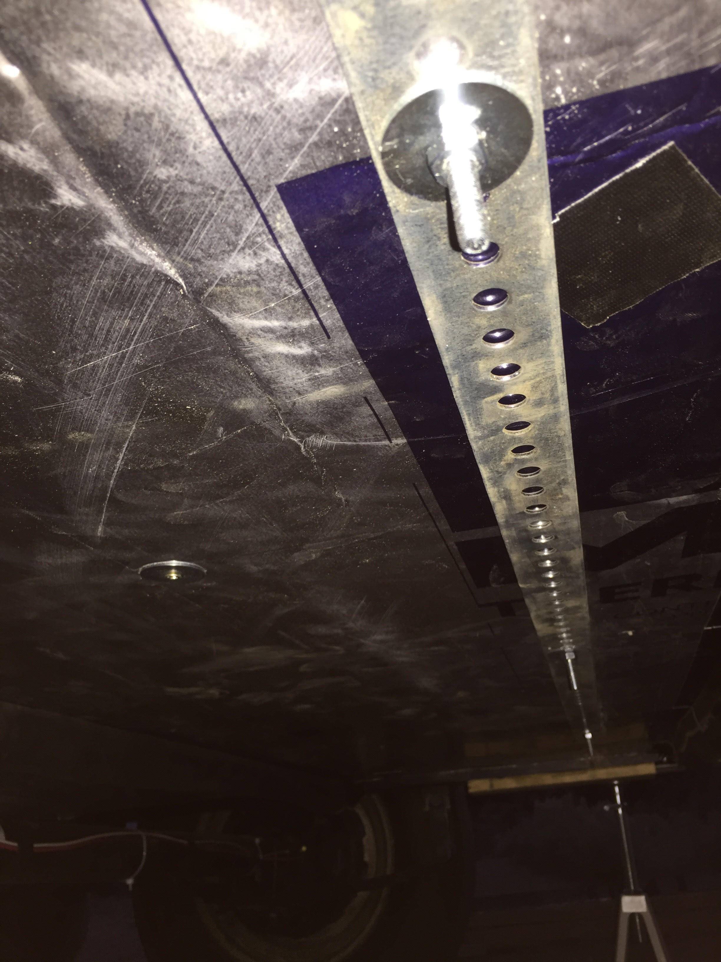 Metal strap with bolts sunk from the subfloor above to keep the insulation in place and snug.